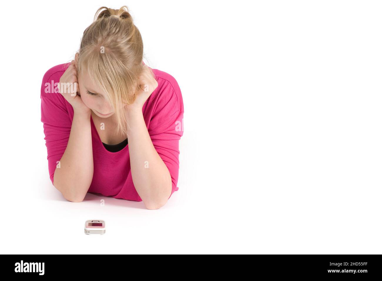 Teenage girl lying down and waiting for a call. Studio shot on white background. Stock Photo