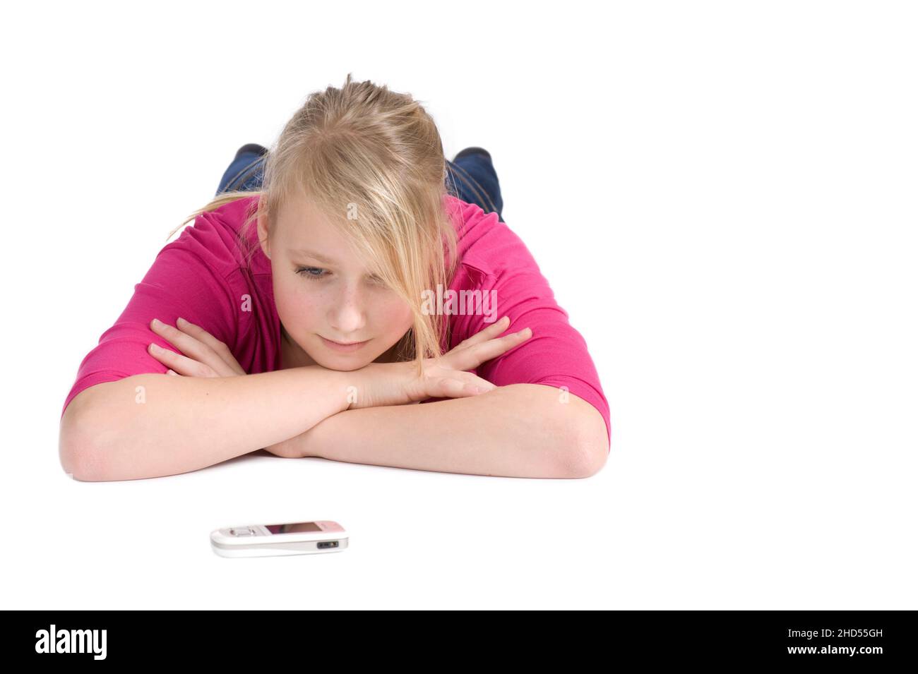 Teenage girl lying down and waiting for a call. Studio shot on white background. Stock Photo
