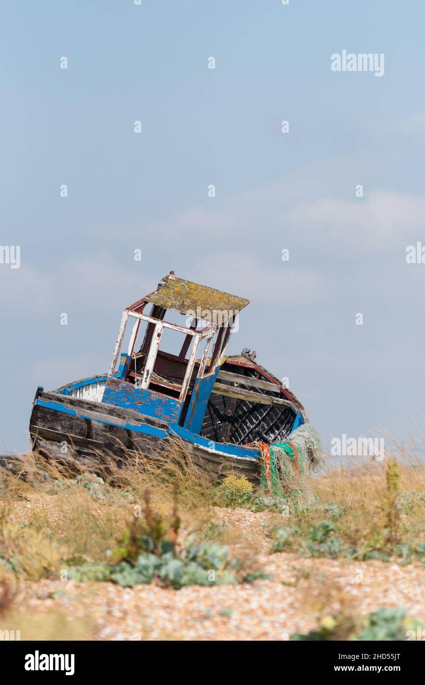 Abandoned derelict fishing boat on the shingle beach above high water ...