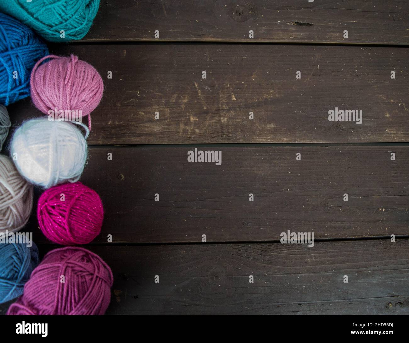 The details are crocheted with their own hands, multicolored yarn lies on a  wooden table Stock Photo by Yashik7777