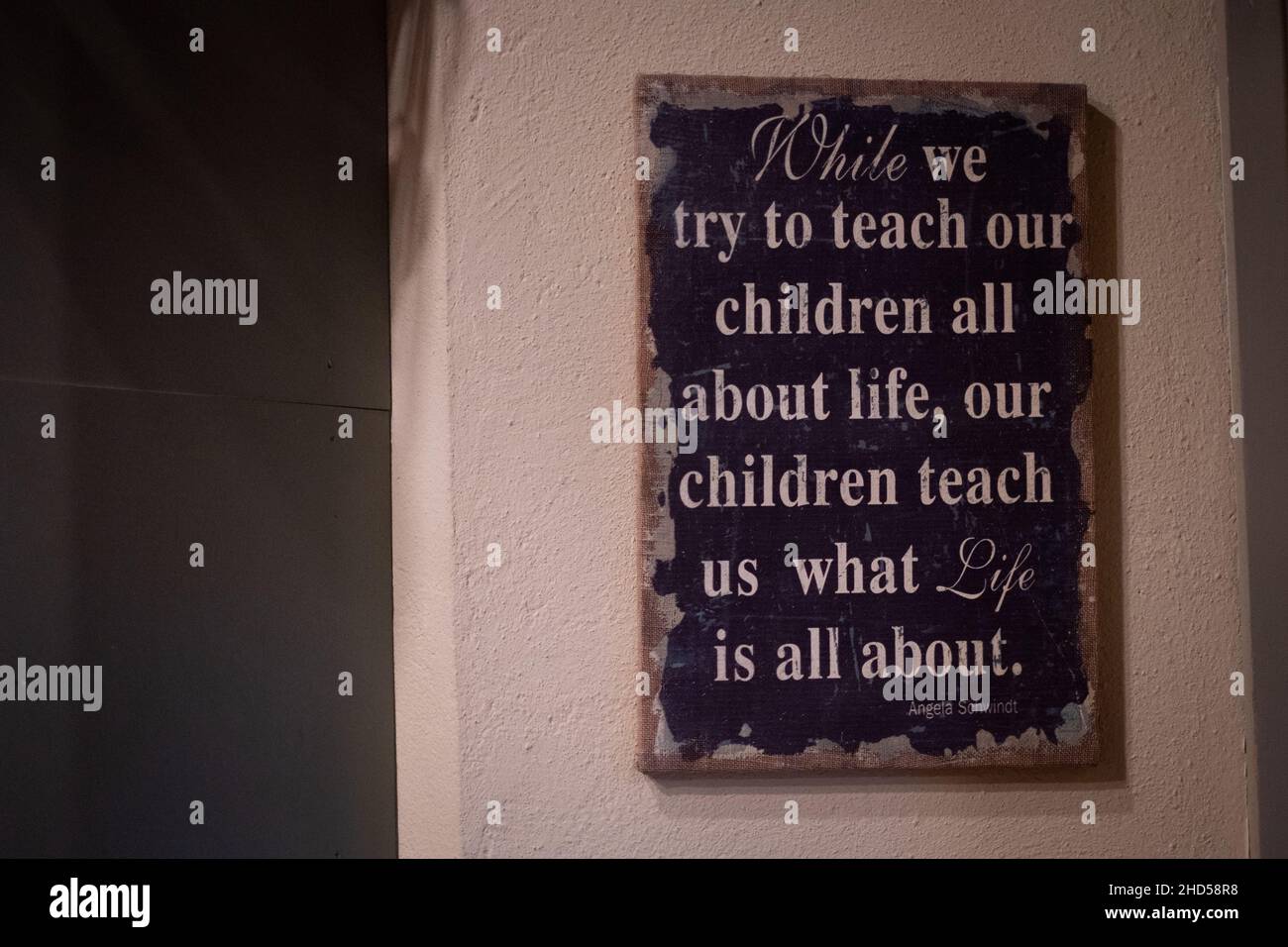 Sign on a wall saying 'While we try to teach our children all about life, our children teach us what life is all about. Lessons of life. Quote Stock Photo