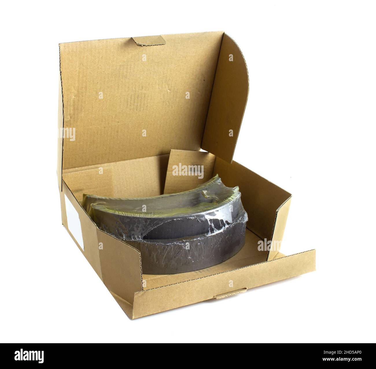 Brown cardboard box with car brake pads isolated on white background. Spare parts for transport Stock Photo