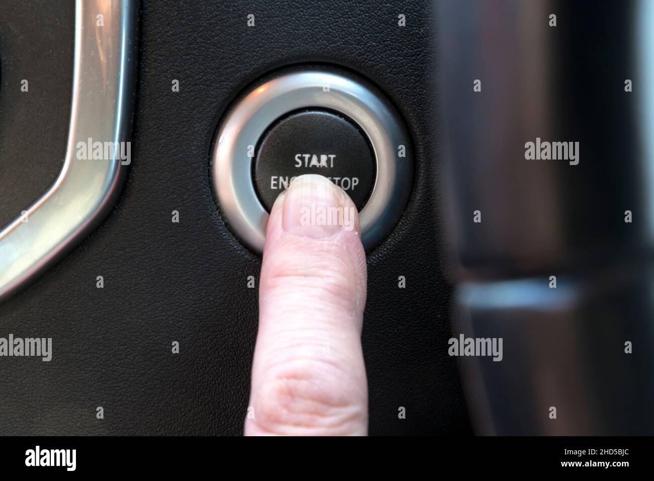 Woman pressing the Engine Stop Start button of a car - in this case a Land Rover Discovery. Stock Photo