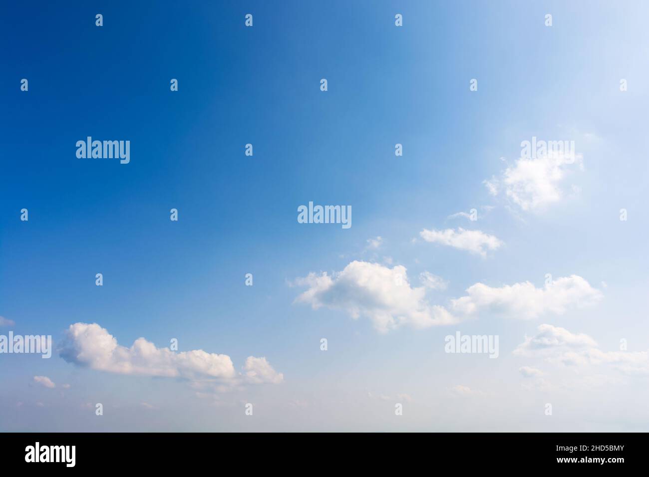 sky with fluffy clouds. white cumulus sparse cloudscape on a deep blue gradient of atmosphere. sunny summer weather. beautiful nature background. mete Stock Photo