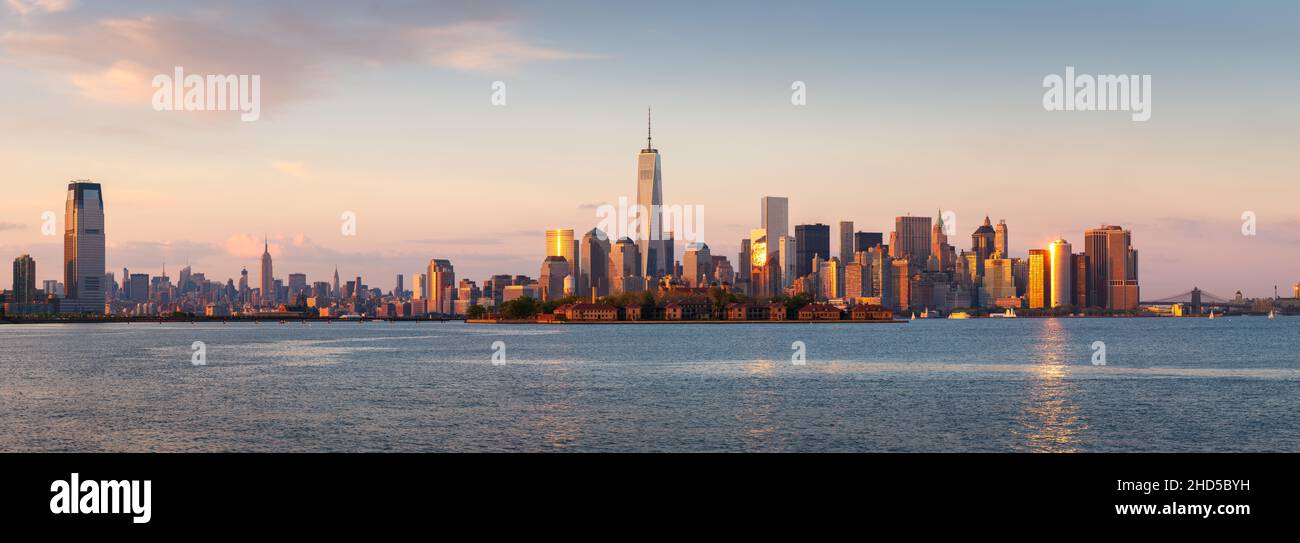 New York City Lower Manhattan skycrapers panoramic view at sunset. Ellis Island in New York Harbor with the World Trade Center Stock Photo