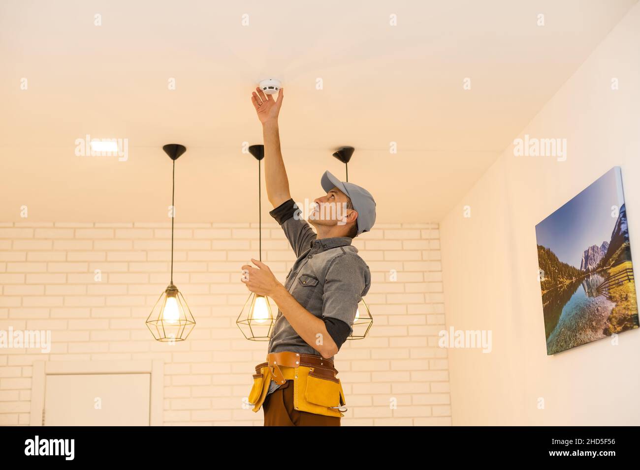 Handyman installing a smoke detector on the ceiling Stock Photo