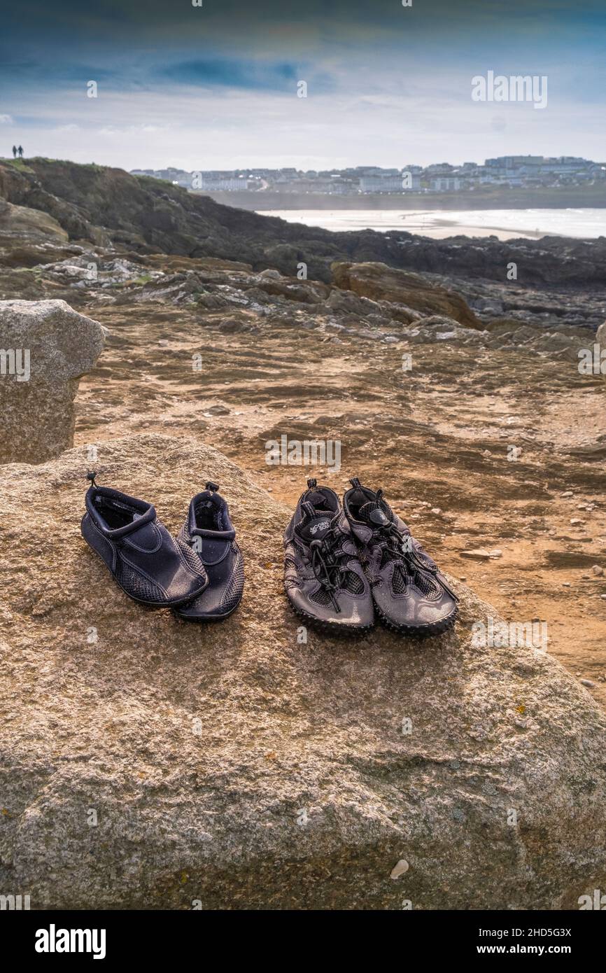 Two pairs of beach shoes on a rock drying out in the sunshine. Stock Photo
