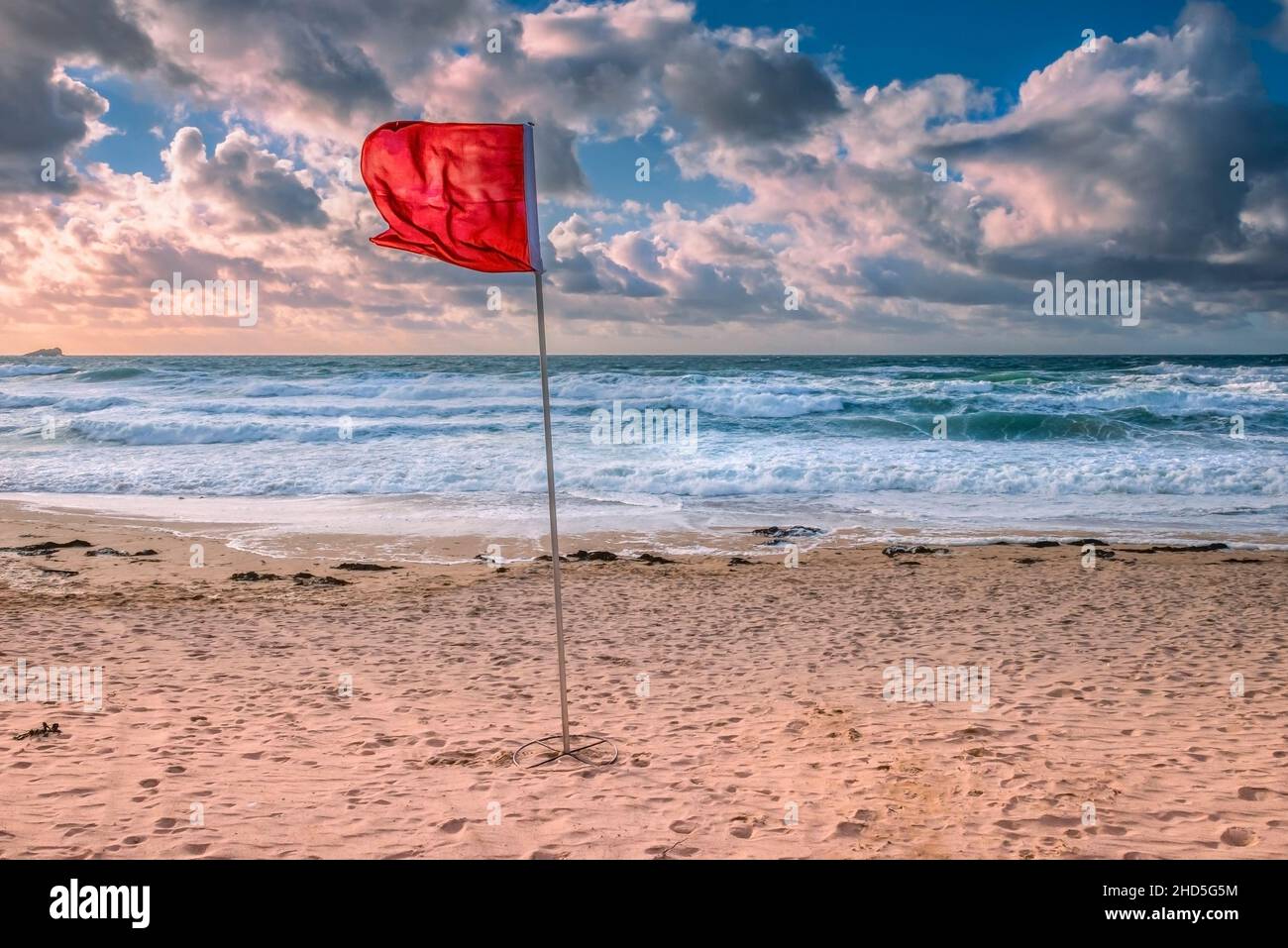 A RNLI red flag for danger fluttering in high winds at Fistral Beach in Newquay in Cornwall. Stock Photo