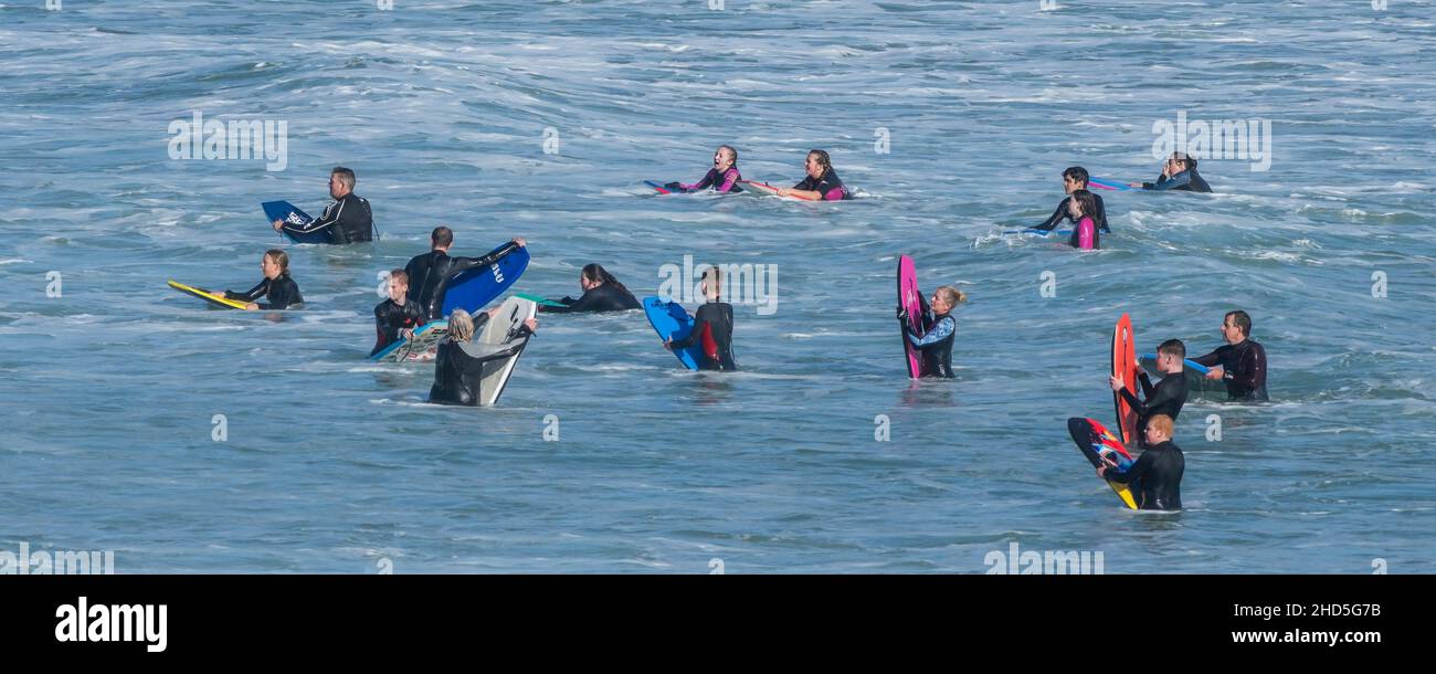 A panoramic image of holidaymakers bodyboarding in the sea at Fistral in Newquay in Cornwall. Stock Photo
