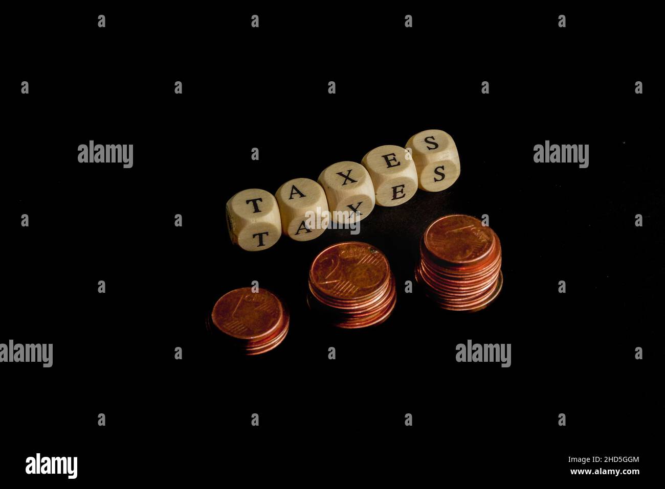 Staples of coins with wooden letters cubes forming the word Taxes in