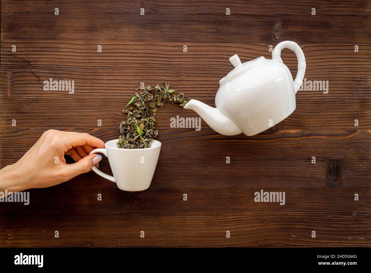 Hand Over Tea Female hand pours tea leaves from teapot in cup Stock Photo - Alamy