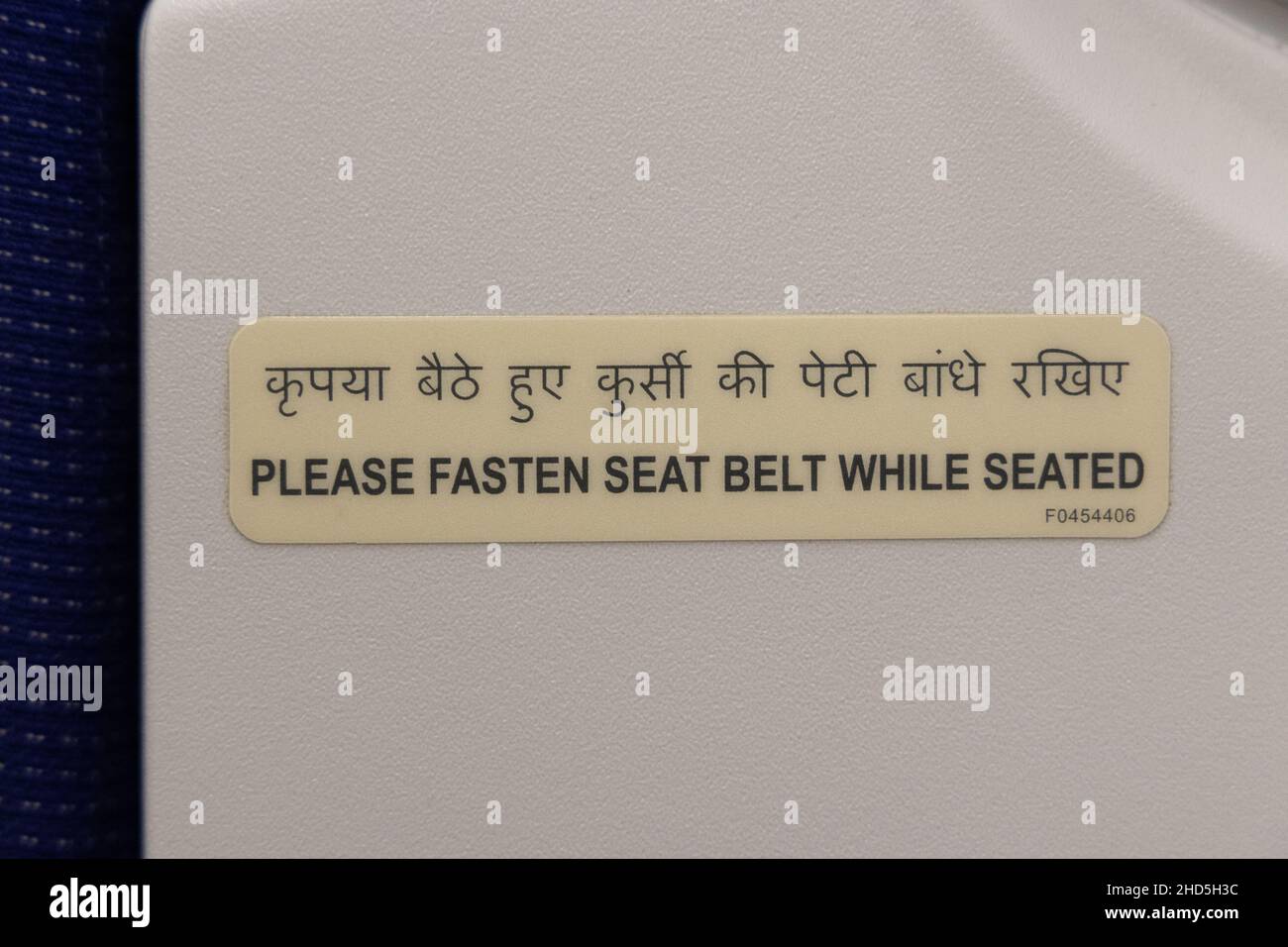 Airplane safety instruction sticker telling to fasten seat belt while