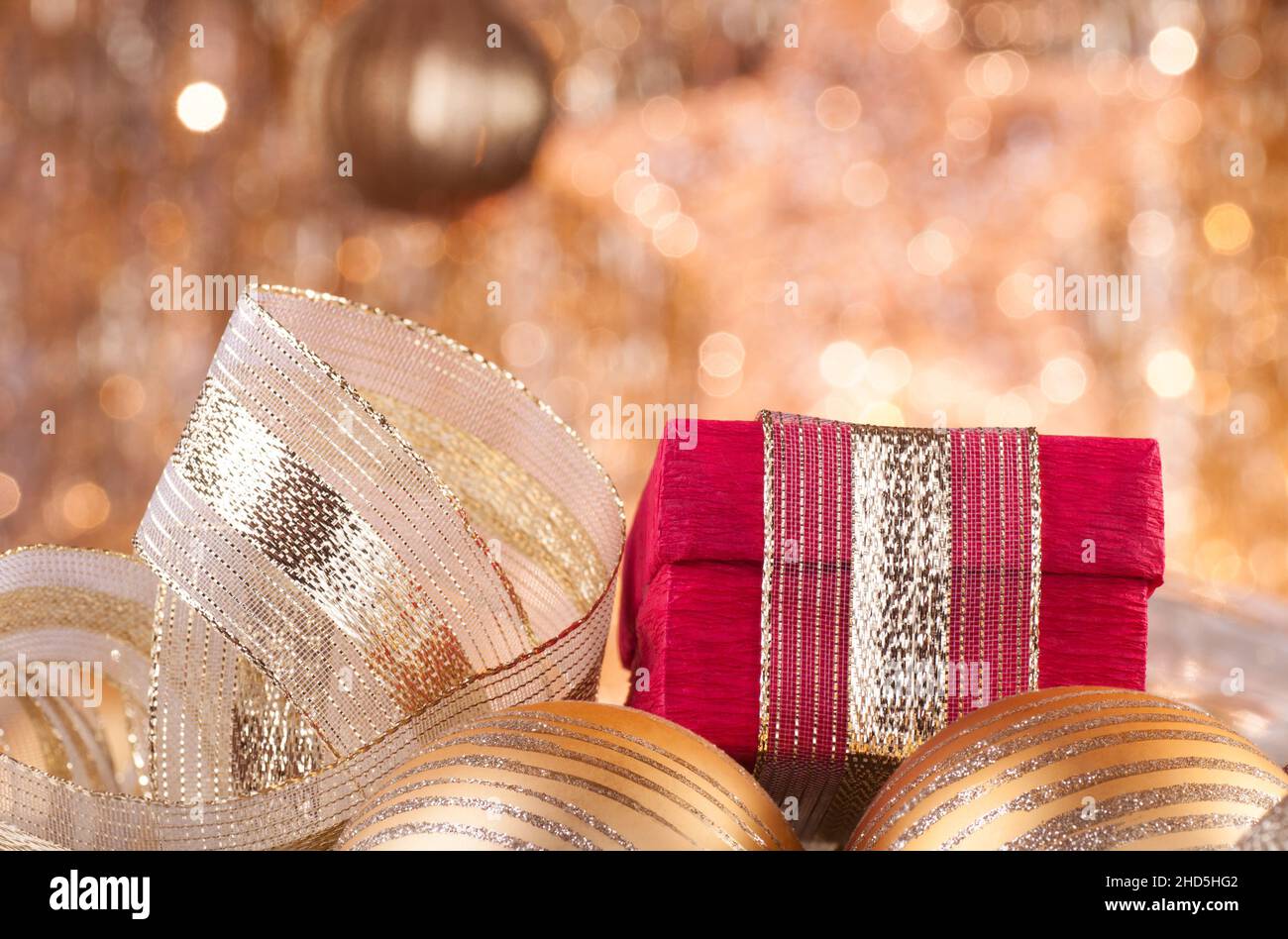 gold christmas baubles and red box on background of defocused golden lights. Stock Photo