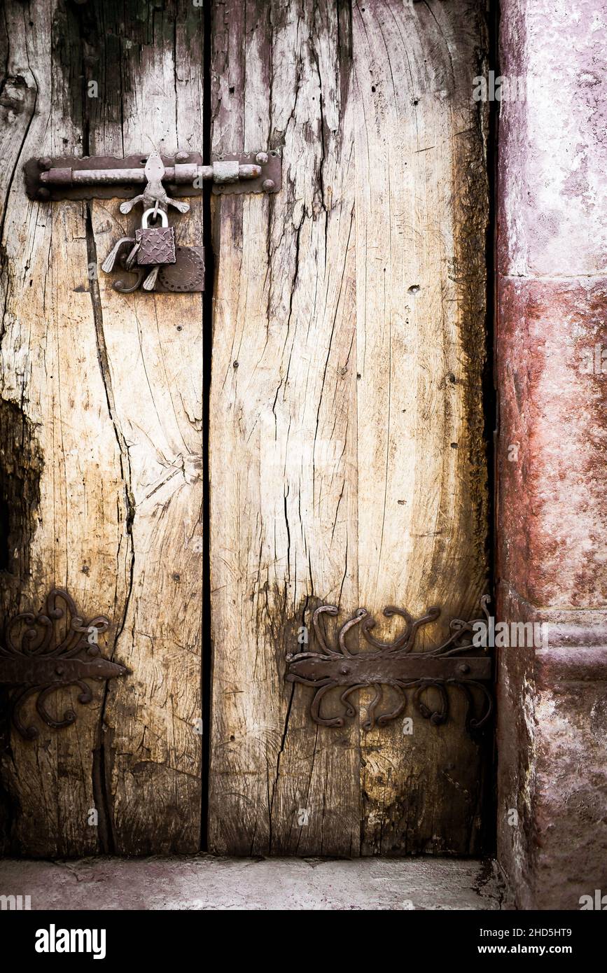 Close up of Hand forged iron door hinges for antique exterior wooden doors with decorative locks in San Miguel de Allende, Mexico, in black and white Stock Photo