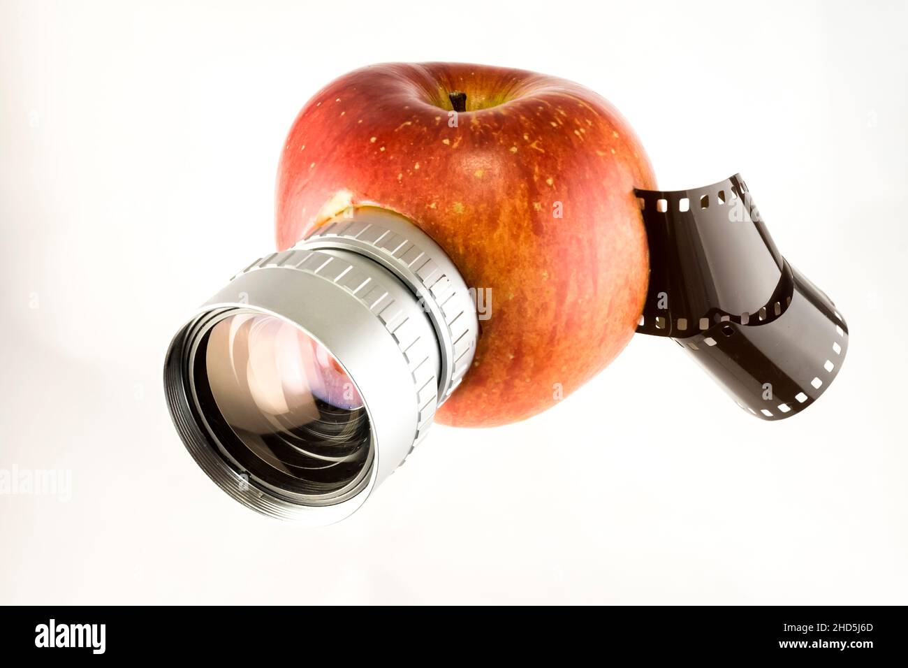 Apple fruit with camera lens and film roll, isolated on white, parody, creative concept Stock Photo