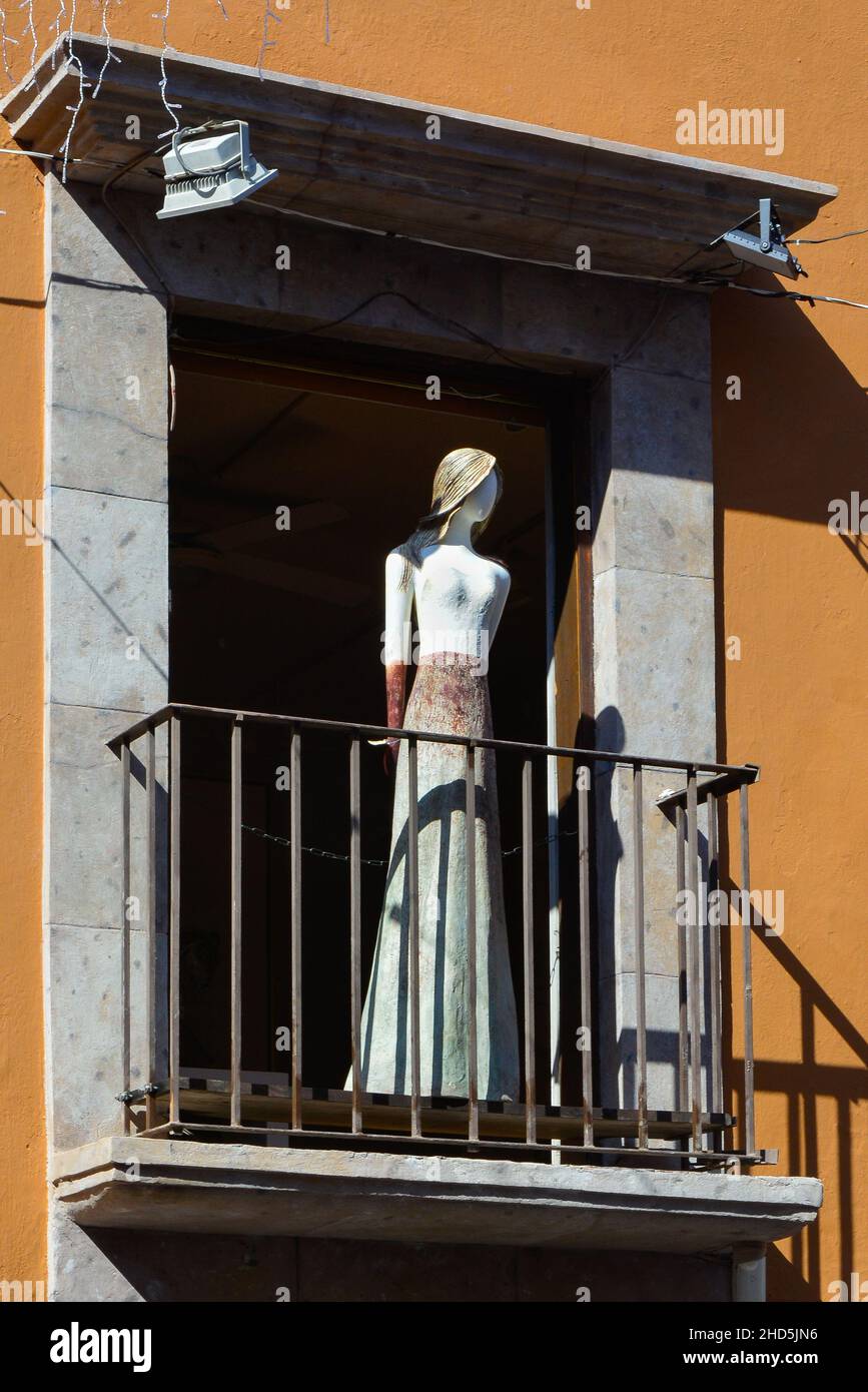 A curious life size stylized sculpture of a woman stands mannequin-like on the balcony of the EXIM Galeria, specializing in local artists, SMA, MX Stock Photo