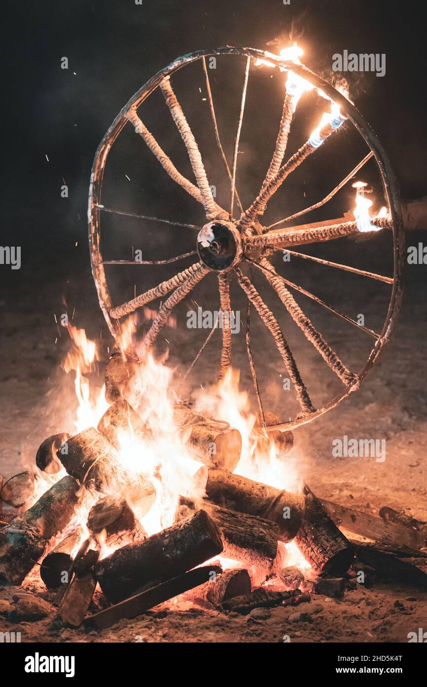 an old wheelchair burning in a fire with flames in the wheels in the dark Stock Photo