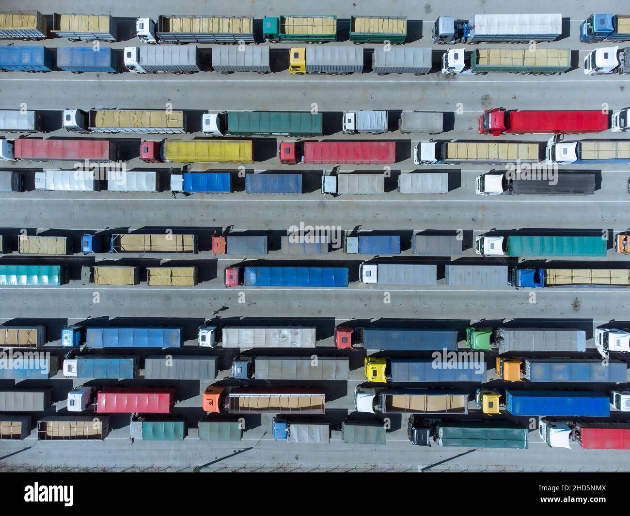 Grain terminals of modern sea commercial port. Many trucks are waiting in line for unloading in port harbor, top view from quadcopter. Stock Photo