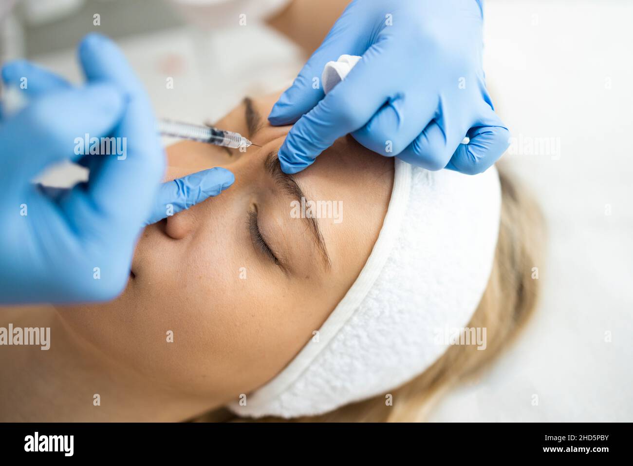 Beautician makes botox injections in the area between the eyebrows. Anti aging procedure Stock Photo