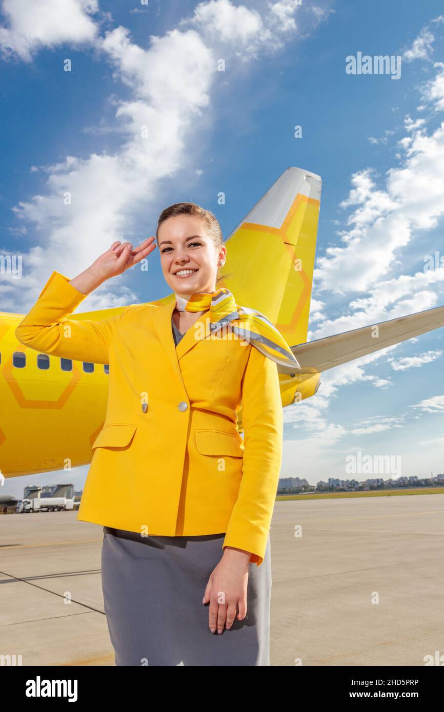 Joyful flight attendant in airline suit doing salute gesture and