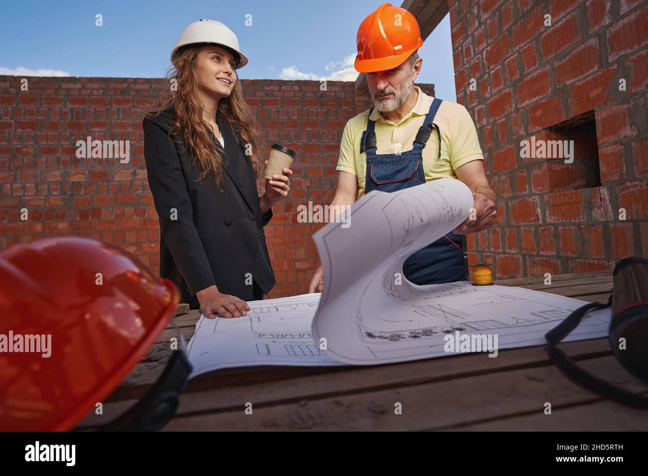 Woman engineer looking to side while worker studying blueprints Stock Photo