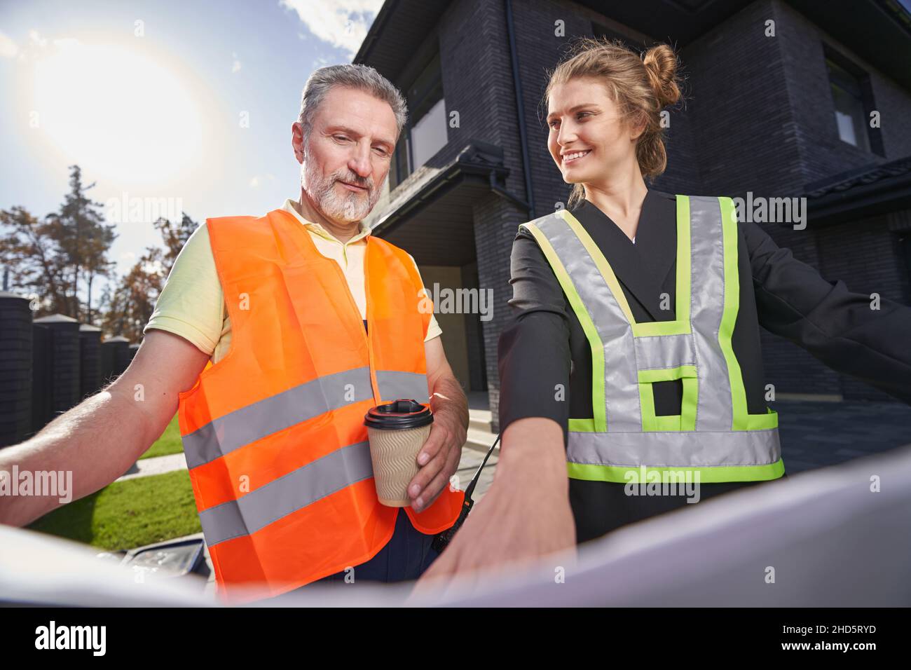 Satisfied construction engineer pointing out something on drawings to worker Stock Photo