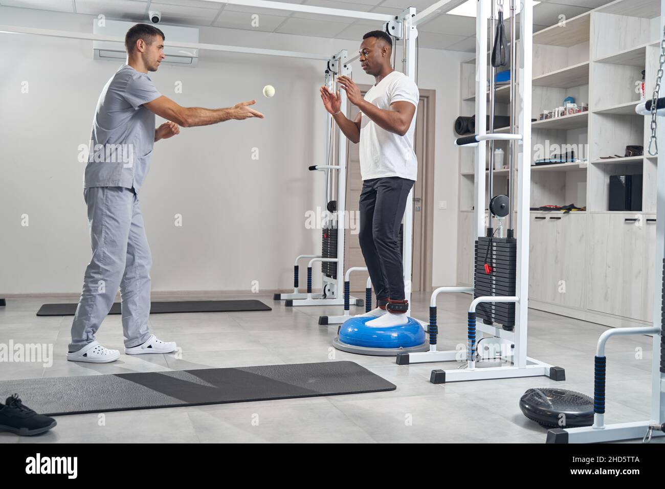 Man with ankle weights working out on balance trainer Stock Photo