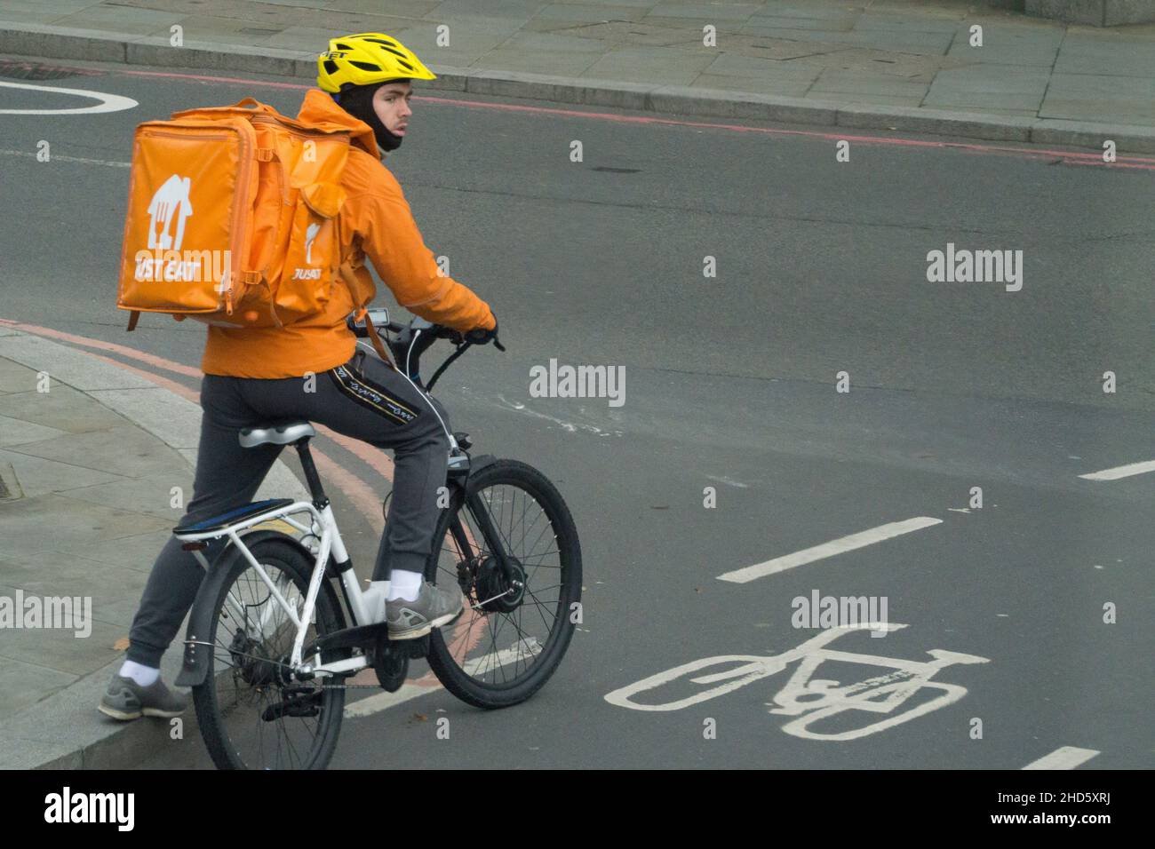 London, UK, 3 January 2022: A Just Eat delivery rider on a bicycle waits in the cycle lane at a junction. Along with Uber Eats and Deliveroo, delivering hot food to customers is a growth sector. Anna Watson/Alamy Live News Stock Photo