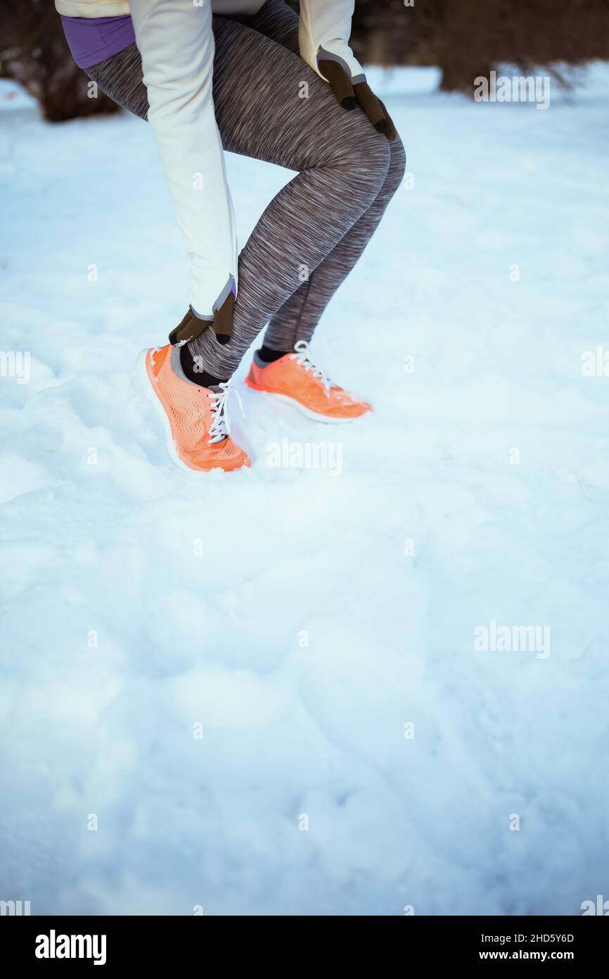 Closeup on woman in white jacket got a leg injury outdoors in the city park in winter. Stock Photo