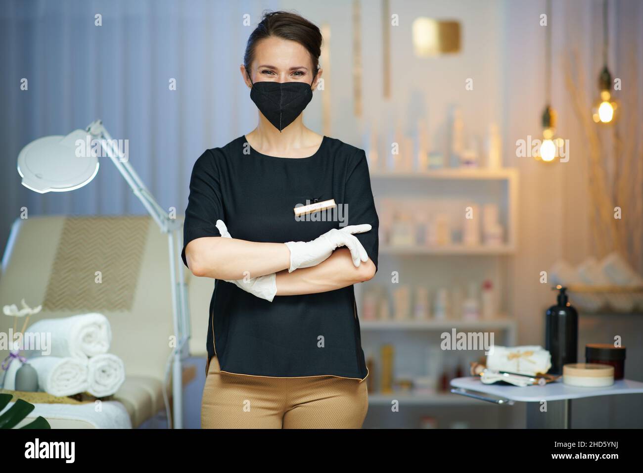 Business during covid-19 pandemic. Portrait of 40 years old woman worker with ffp2 mask in modern beauty studio. Stock Photo