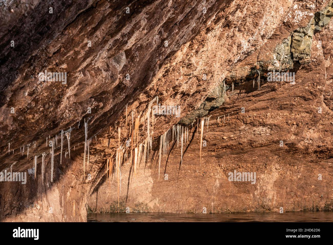 Red sandstone conglomerate overhang with icicles, Rode O, Rodefjord, Scoresby Sund, Greenland Stock Photo