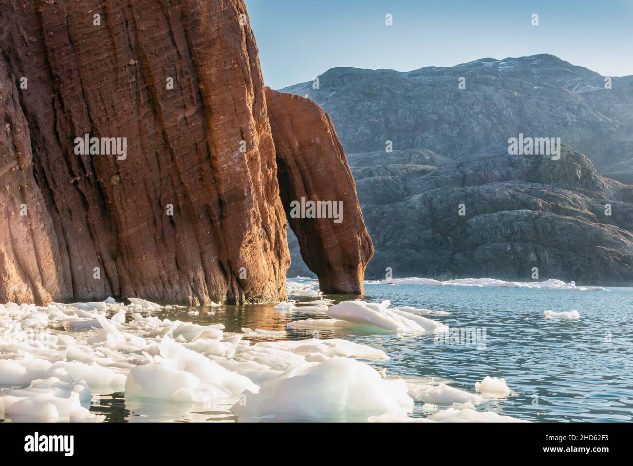 Sandstone arch with ice floes, Rode O with Milne Land in BG, Rodefjord, Scoresby Sund, Greenland Stock Photo