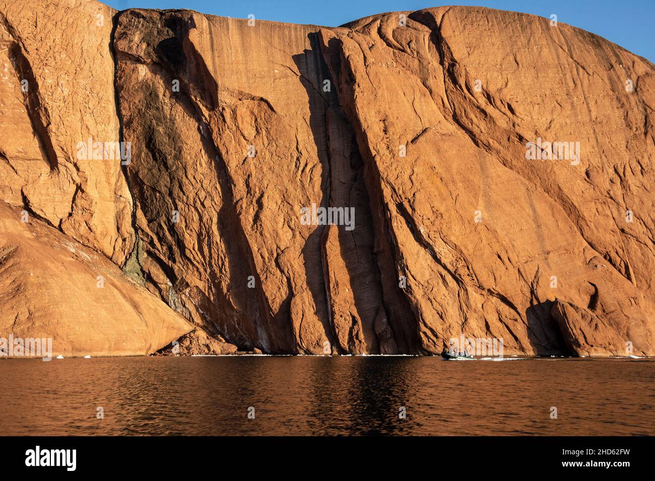 Zodiac by the cliffs of Rode O, Rodefjord, Scoresby Sund, Greenland Stock Photo