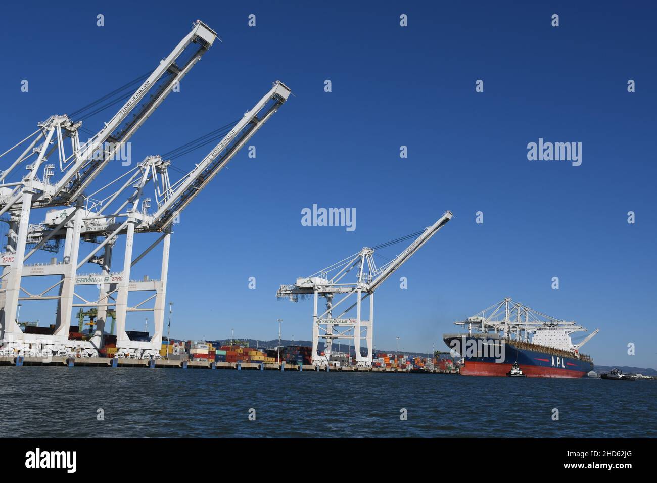 Tugs docking container ship APL President Eisenhower, Port of Oakland. Commercial freight and container ships in San Francisco Bay, California Stock Photo