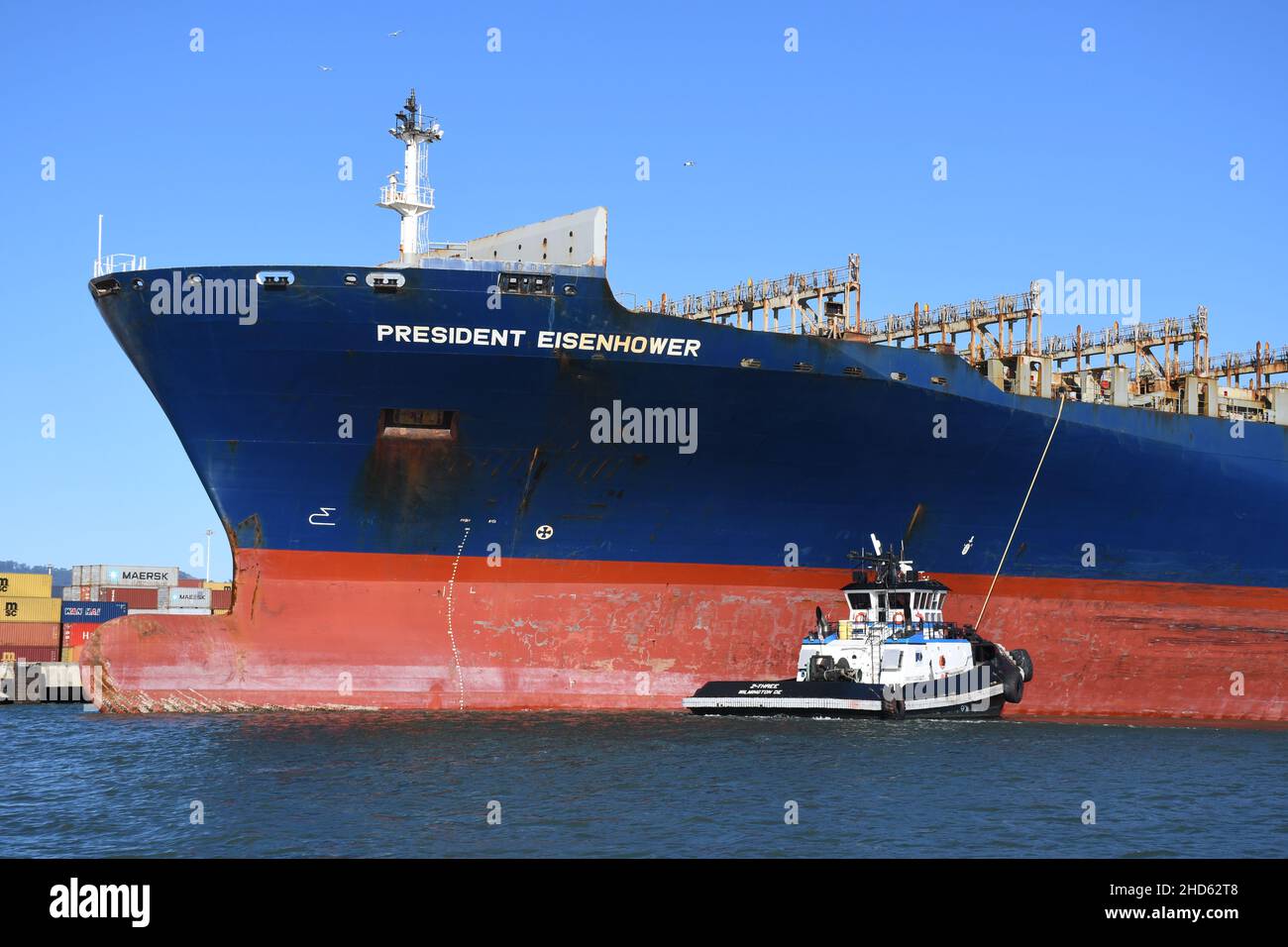 Tugs docking container ship APL President Eisenhower, Port of Oakland. Commercial freight and container ships in San Francisco Bay, California Stock Photo