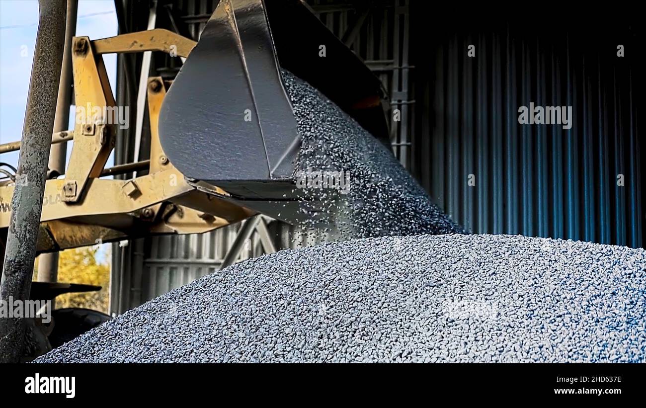 https://c8.alamy.com/comp/2HD637E/side-view-of-excavator-flipping-the-bucket-with-gravel-professional-machine-with-a-bucket-fully-loaded-filling-metal-hangar-with-small-crushed-stones-2HD637E.jpg