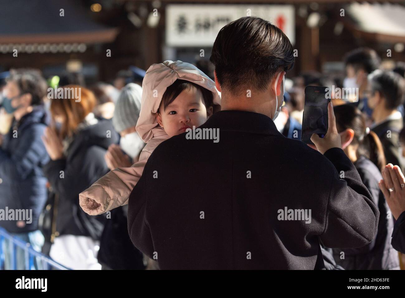 Tokyo, Japan. 03rd Jan, 2022. Father with his child takes a photo with his mobile phone during Hatsum?de at Meiji Jingu Shrine in Shibuya. Hatsum?de is the Japanese tradition of visiting a shrine or temple for the first time in the New Year. On this occasion, people pray for good fortune and health in the year ahead. Credit: SOPA Images Limited/Alamy Live News Stock Photo