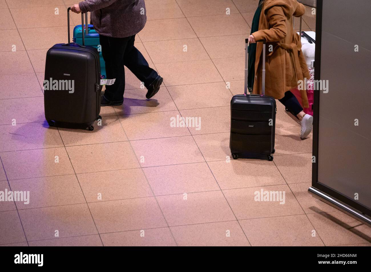 Hamburg, Germany. 04th Jan, 2022. Returning passengers of the cruise ship 'Aida Nova' walk through the arrivals area of Hamburg airport with their suitcases during the night after being brought back to Germany by one of two chartered planes. The shipping company Aida Cruises had decided to cancel the voyage of the 'Aida Nova' in Lisbon after the cases of infection with Covid-19 among the crew. Credit: Jonas Walzberg/dpa/Alamy Live News Stock Photo