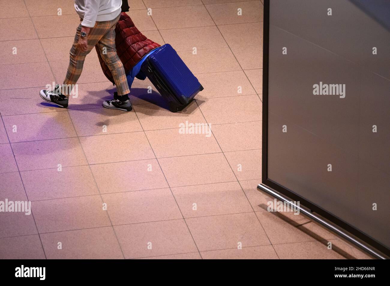 Hamburg, Germany. 04th Jan, 2022. A returning passenger of the cruise ship 'Aida Nova' walk with their suitcases through the arrivals area of Hamburg airport during the night after being brought back to Germany by one of two chartered planes. The shipping company Aida Cruises had decided to cancel the voyage of the 'Aida Nova' in Lisbon after the cases of infection with Covid-19 among the crew. Credit: Jonas Walzberg/dpa/Alamy Live News Stock Photo