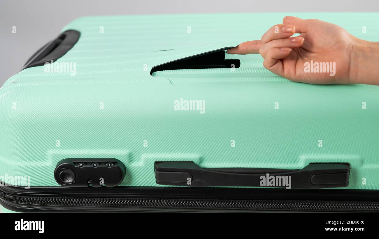 A woman demonstrates a broken suitcase on a white background. Damaged