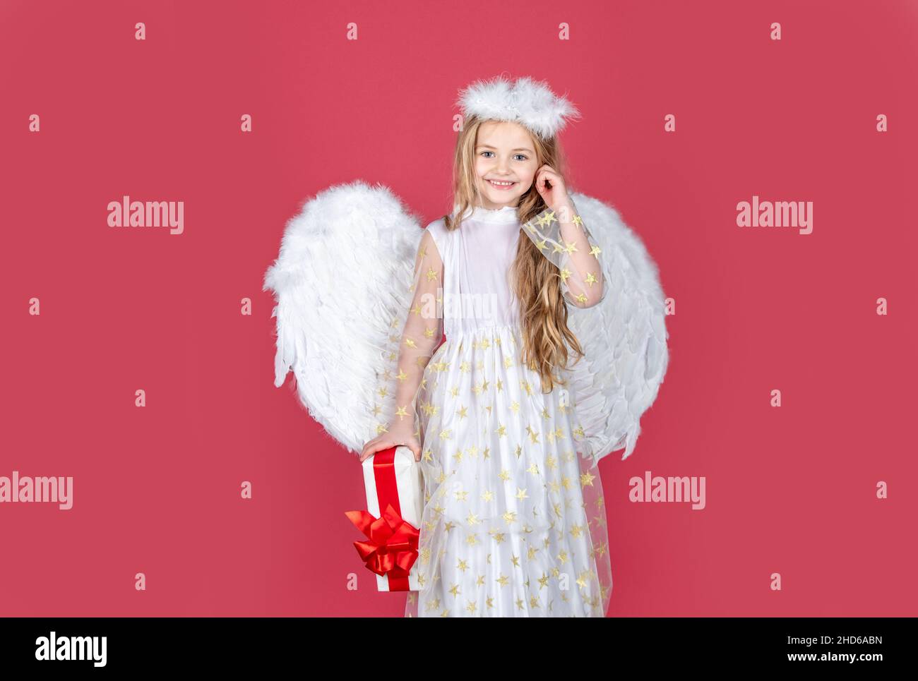 Playful angelic little girl. Little blonde angel with white wings holds ...
