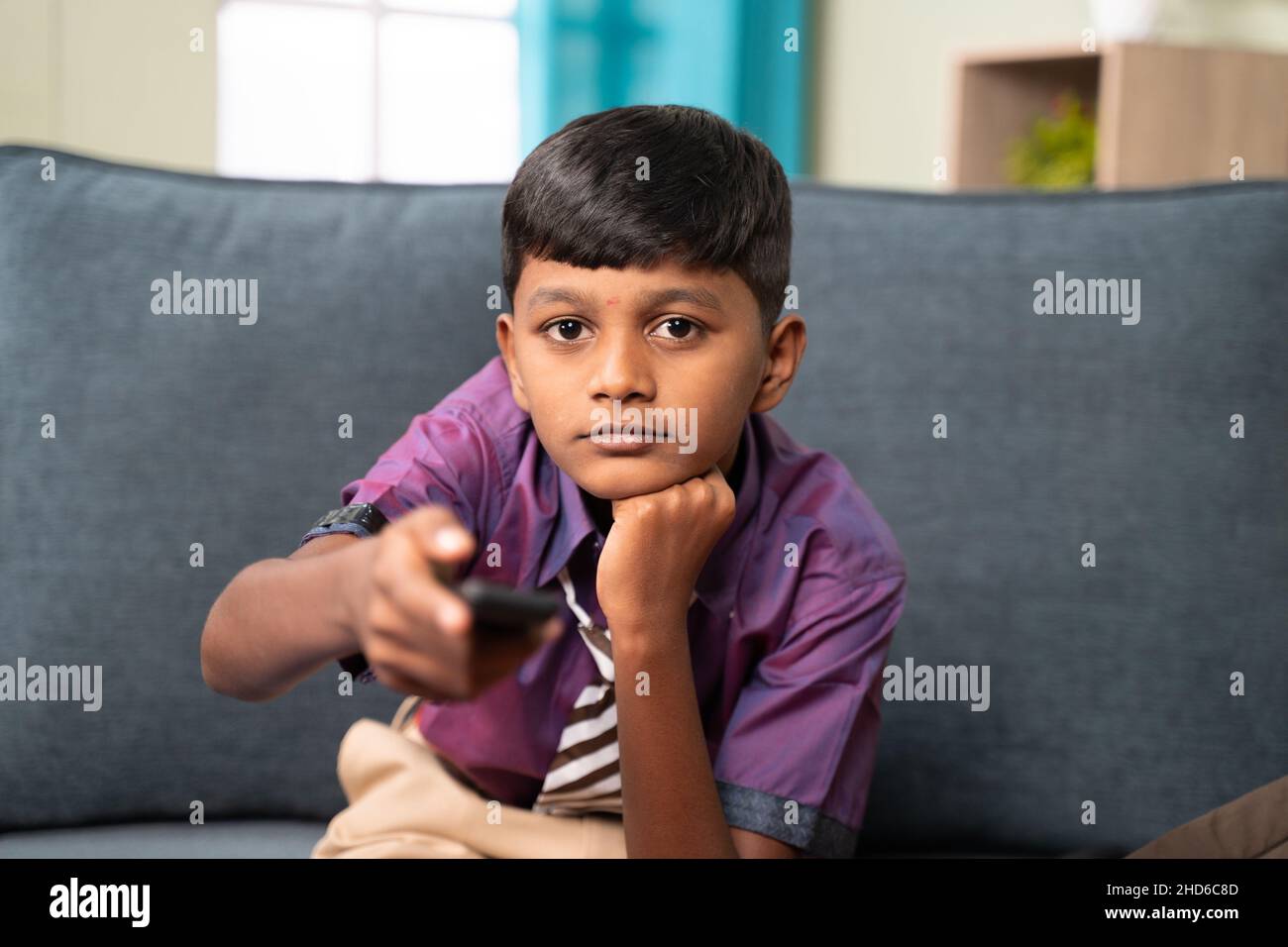 Kid to watch television or tv show after coming from school - concept of childhood movie addiction and unhealthy lifestyle. Stock Photo