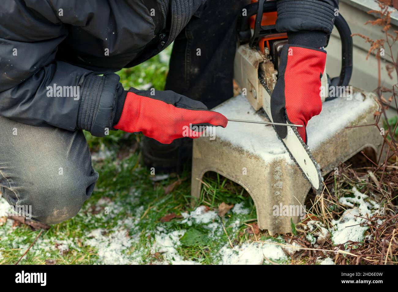 a worker sharpening a chainsaw with file, outdoor close up Stock Photo