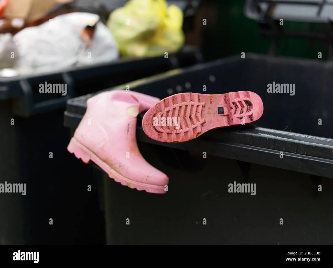 Pink torn rubber boots in a garbage container, shallow DOF, outdoor ...