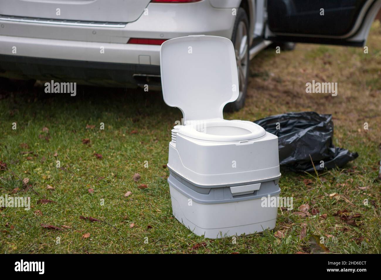a portable potty next to a vehicle with open door, outdoor image Stock Photo