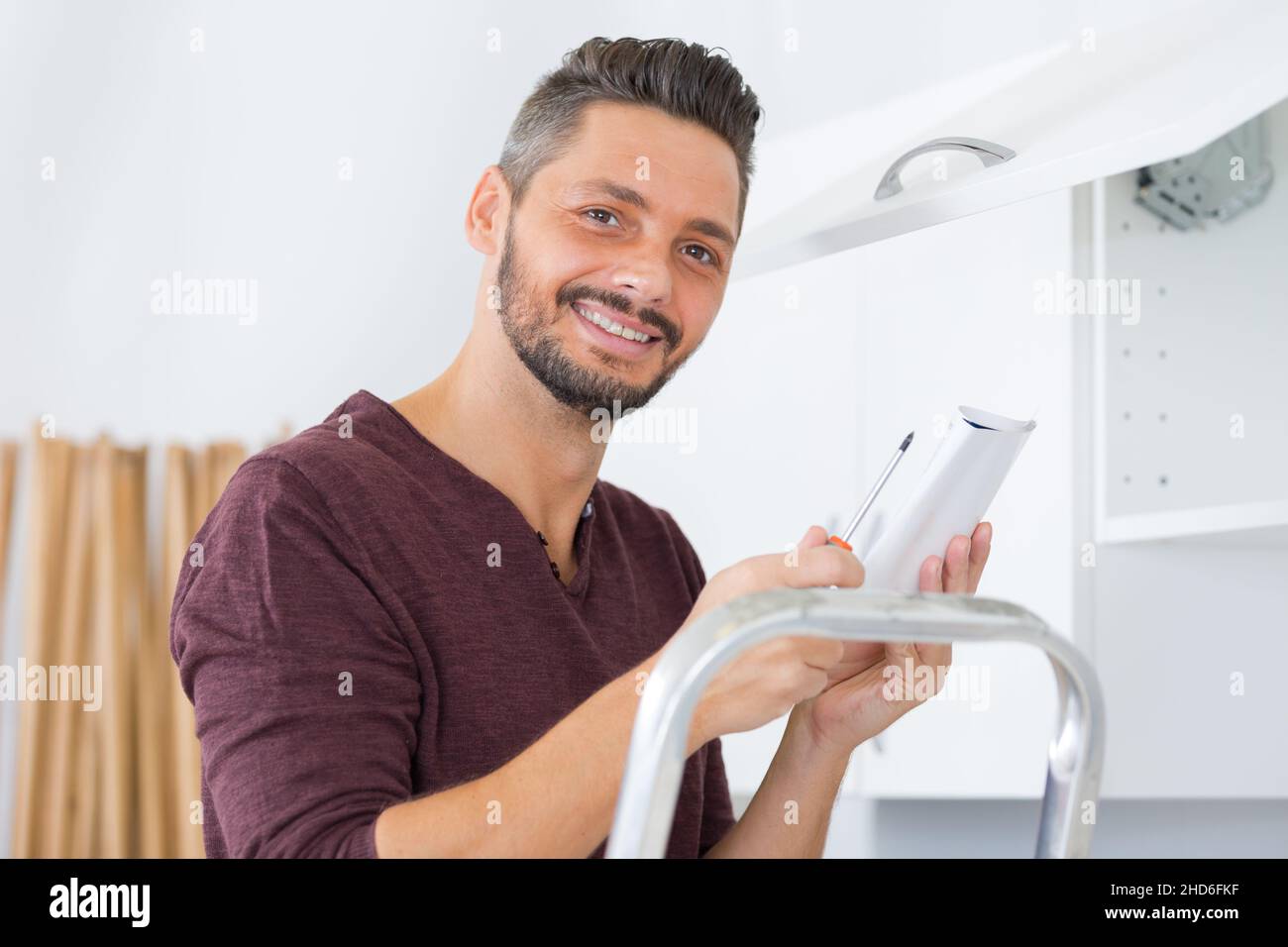 serviceman in overall working on cupboard Stock Photo