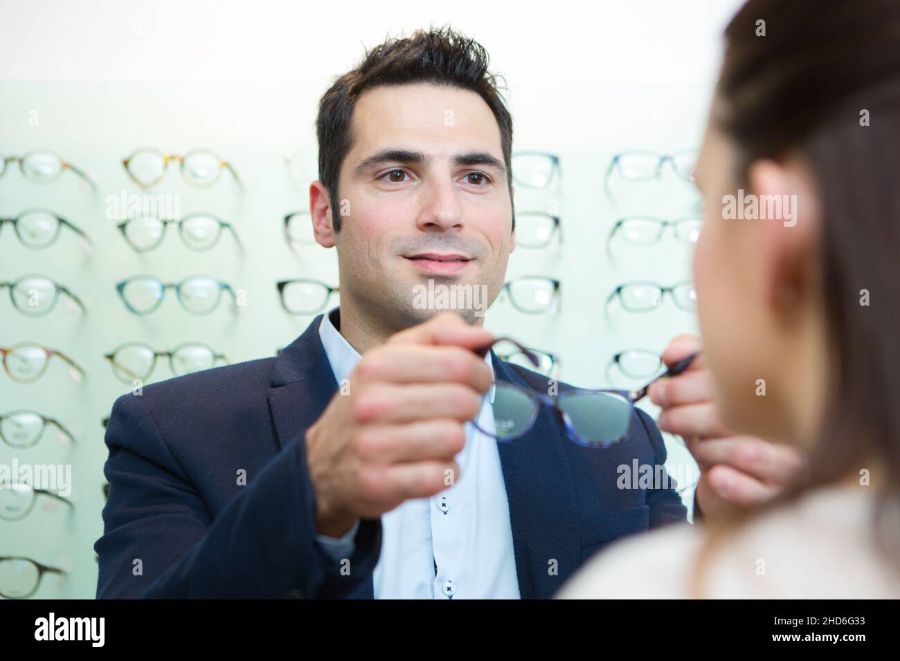 attractive optician assisting female testing new glasses Stock Photo