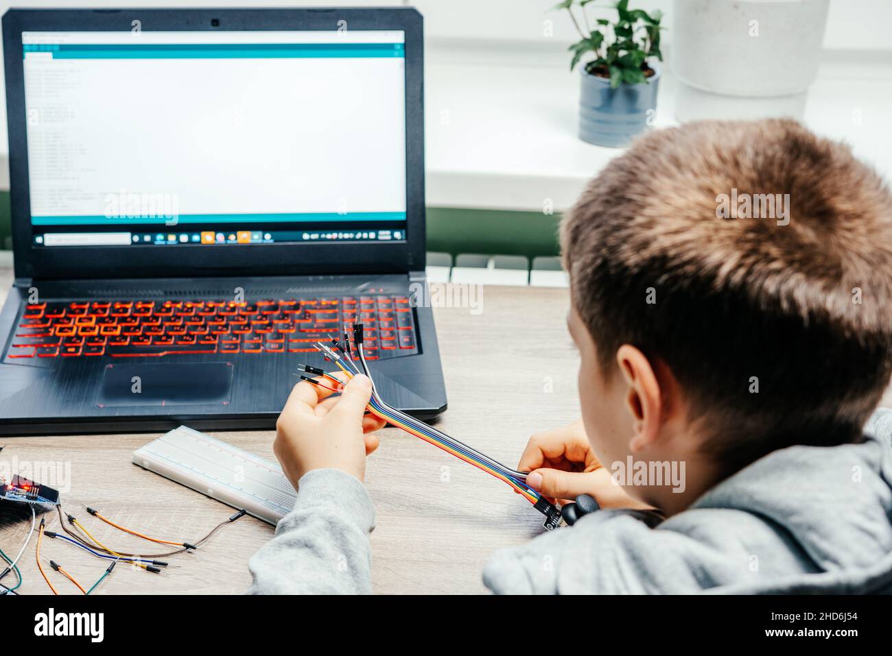 A boy plugging cables to sensor chips while learning arduino coding and ... image.