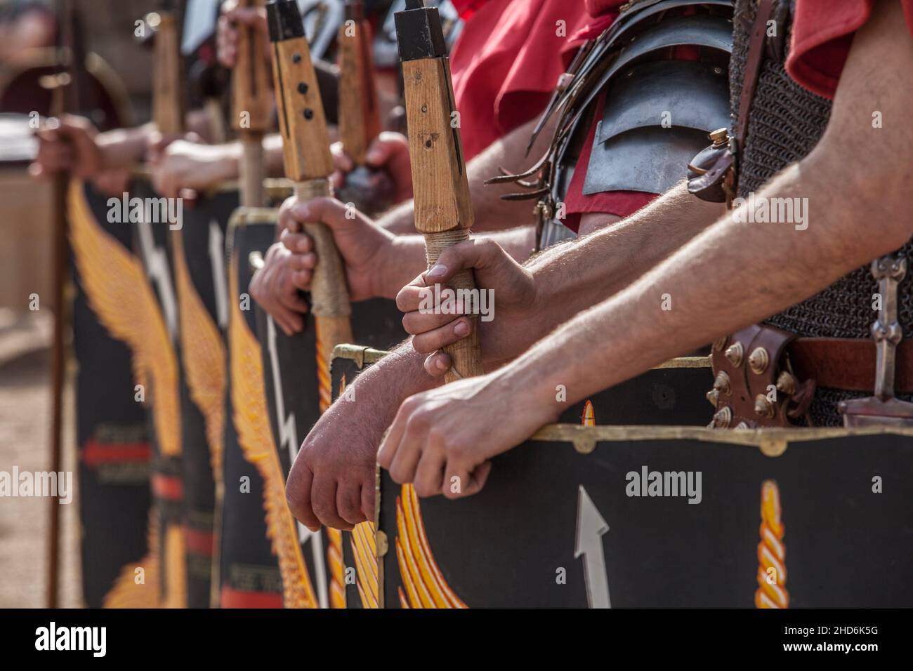 Roman legionaries in formation. Hands holding pila or javelins. Faint eagle-wing and thunderbolt motifs on the scuta. Stock Photo