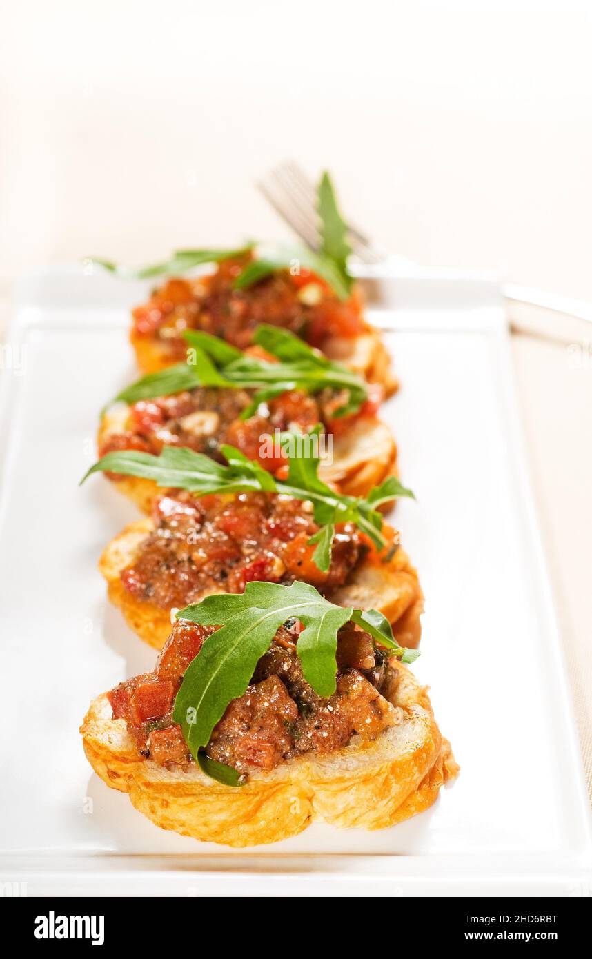 fresh tipycal italian bruschetta with tomato and arugula on top. Stock Photo